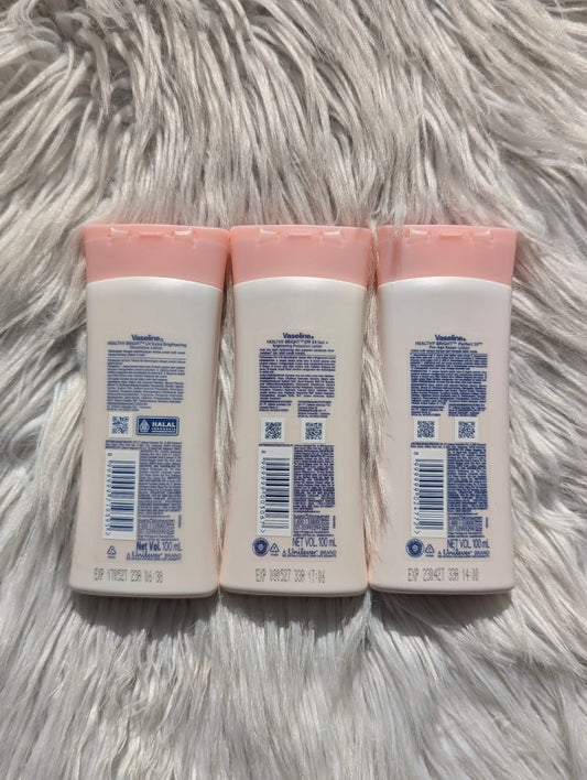 Three baby lotion bottles with pink caps on a fluffy white surface