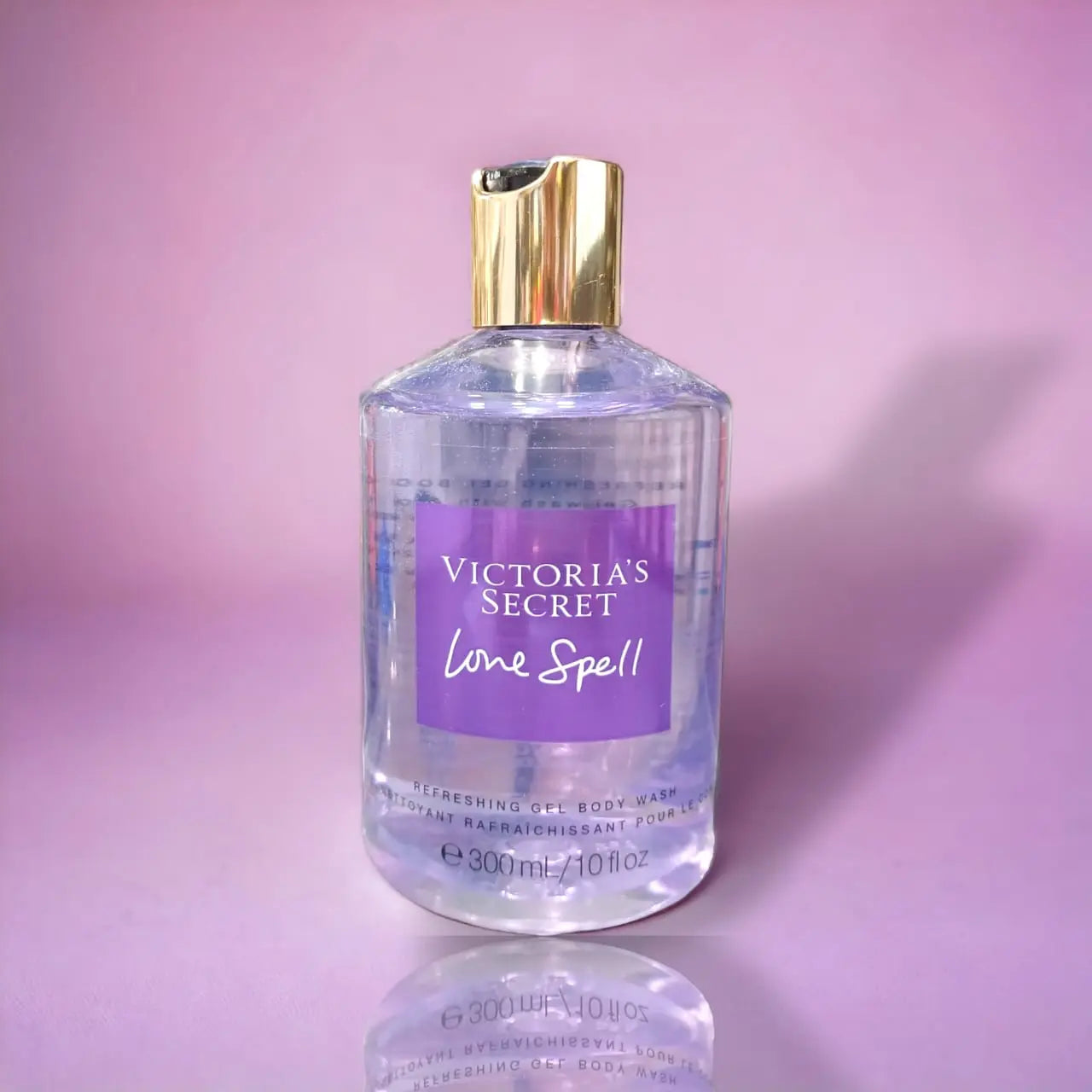 Victoria's Secret Love Spell Refreshing Gel Body Wash 300ml bottle with purple label and gold cap on pink background