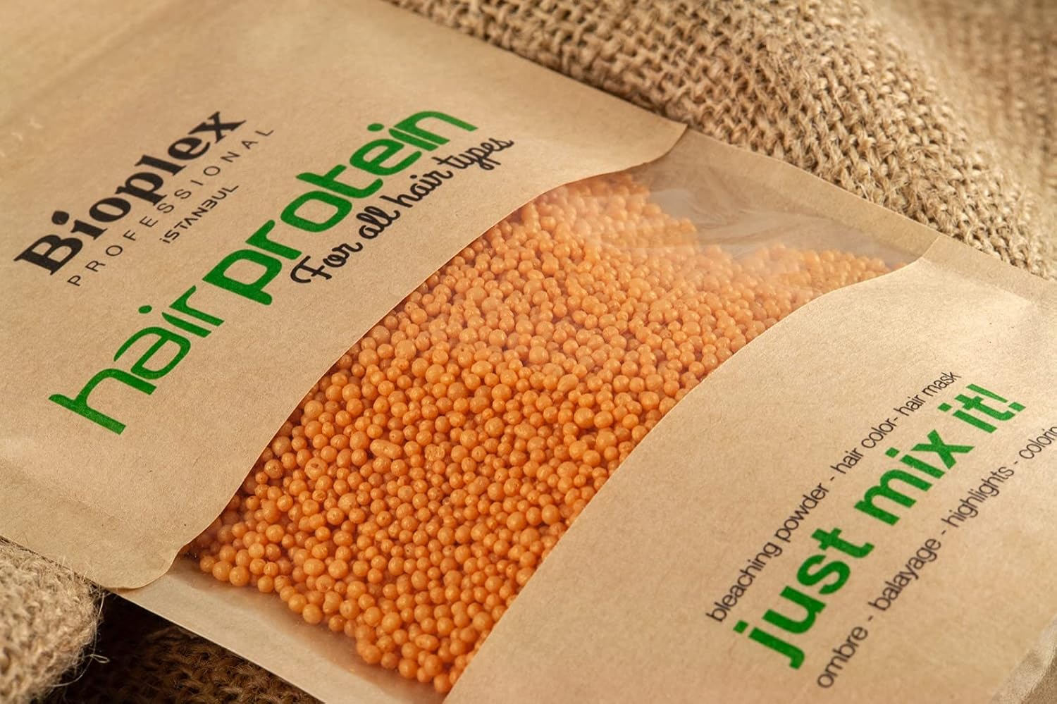 Bioplex hair protein powder package with orange beads inside, on a textured fabric background.
