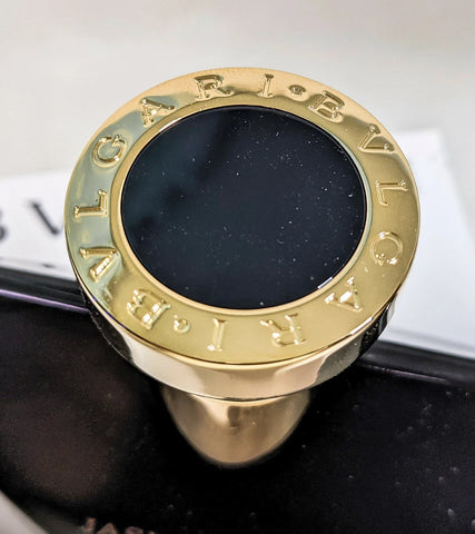 Perfume Bottle Cap with 'BVLGARI' engraving on a black background