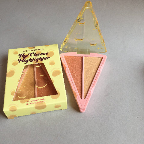 Triangular cheese-shaped highlighter with packaging on a gray background