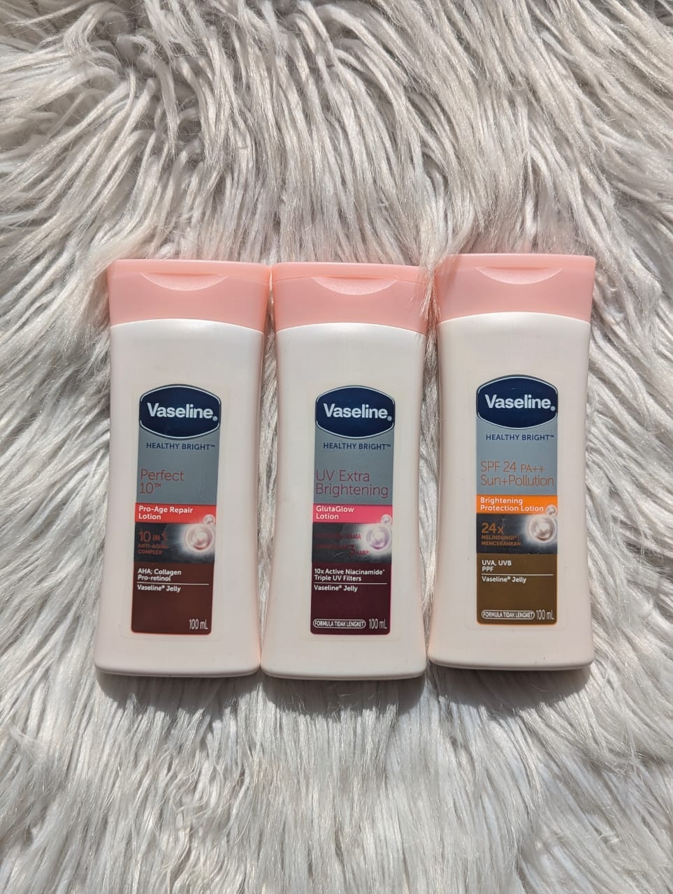 Three Vaseline body lotion bottles on a fluffy white surface