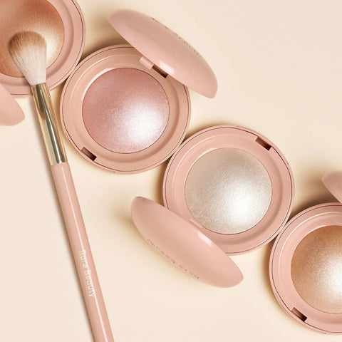 Pink makeup compact with a brush on a light beige background